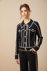 Woman wearing black jacket and trousers set with white piping detail on edges matching outfit for formal or business occasions