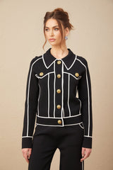 Woman wearing black jacket and trousers set with white piping detail