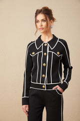 Woman wearing black jacket and trousers set with white piping detail