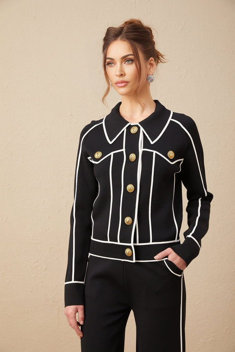 Woman wearing black jacket and trousers set with white piping detail
