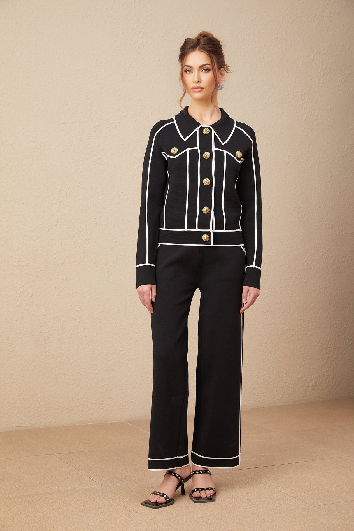 Woman wearing black jacket and trousers set with white piping detail