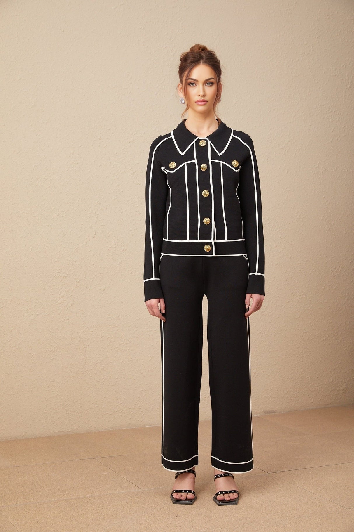 Woman wearing black jacket and trousers set with white piping detail