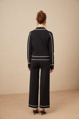 Woman wearing black jacket and trousers set with white piping trim stylish matching outfit