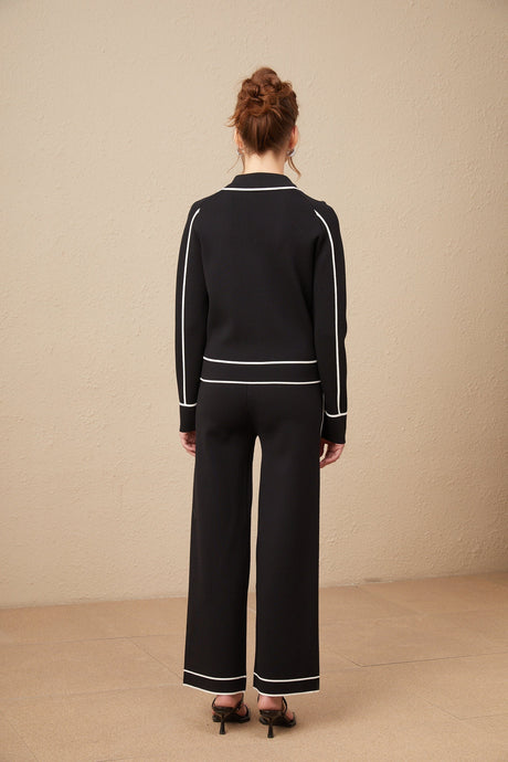 Woman wearing black jacket and trousers set with white piping trim stylish matching outfit