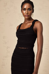 Woman wearing black knitted matching set with ruffled top and skirt