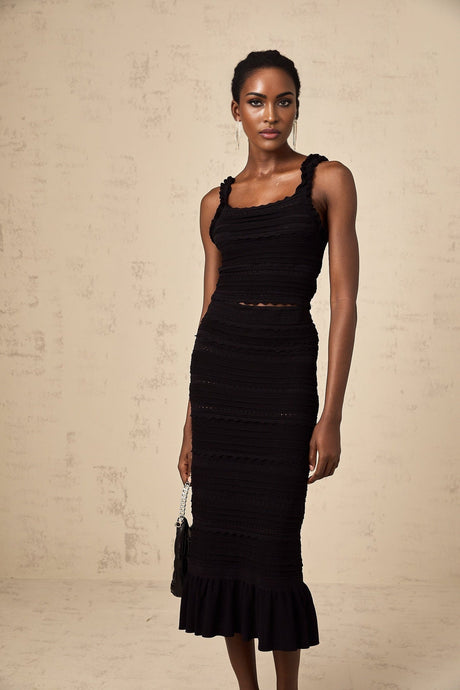 Woman wearing black knitted matching set with ruffled top and skirt