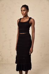 Woman wearing black knitted matching set with ruffled top and skirt