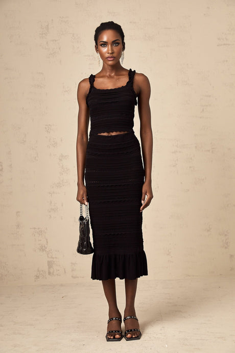 Woman wearing black knitted matching set with ruffled top and skirt