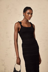 Woman wearing black knitted matching set with ruffled top and skirt