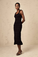 Woman wearing black knitted matching set with ruffled top and skirt