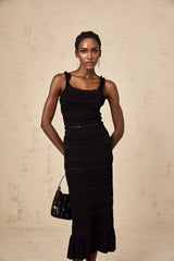 Woman wearing black knitted matching set with ruffled top and skirt