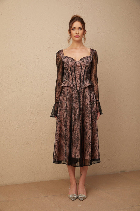 Woman wearing black lace midi dress with flared skirt and long sleeves standing against plain background