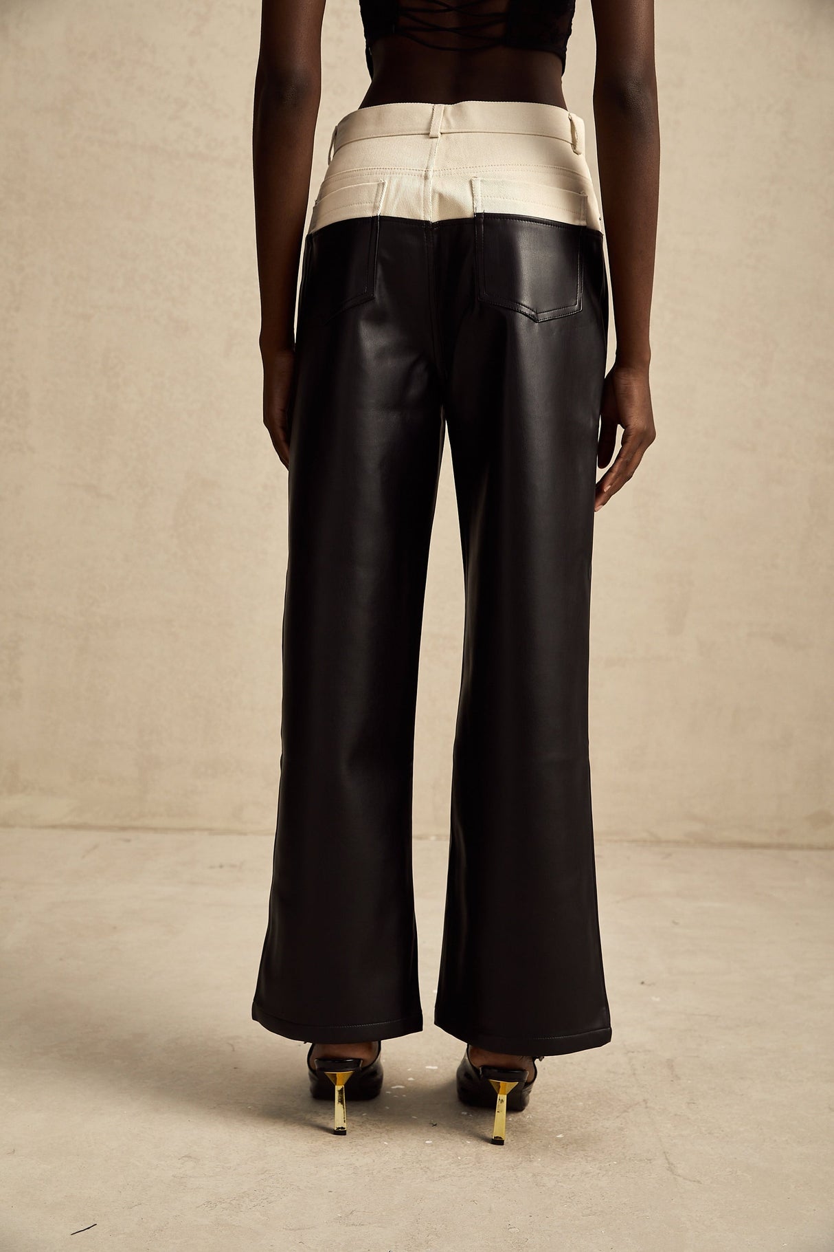 Woman wearing black leather trousers with contrasting white side panels standing in a neutral pose