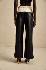 Woman wearing black leather trousers with contrasting white side panels standing in a neutral pose