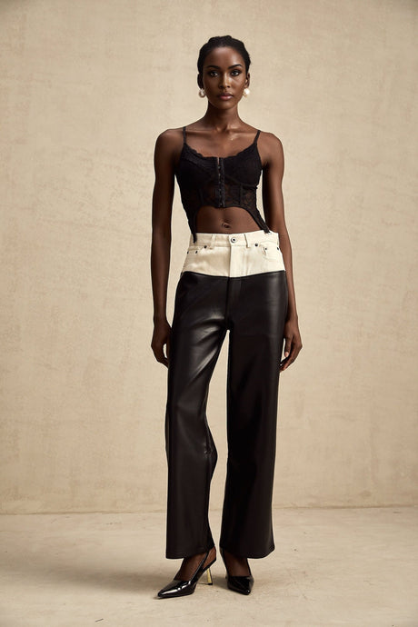 Woman wearing black leather trousers with white contrast stitching and side panels standing in casual pose