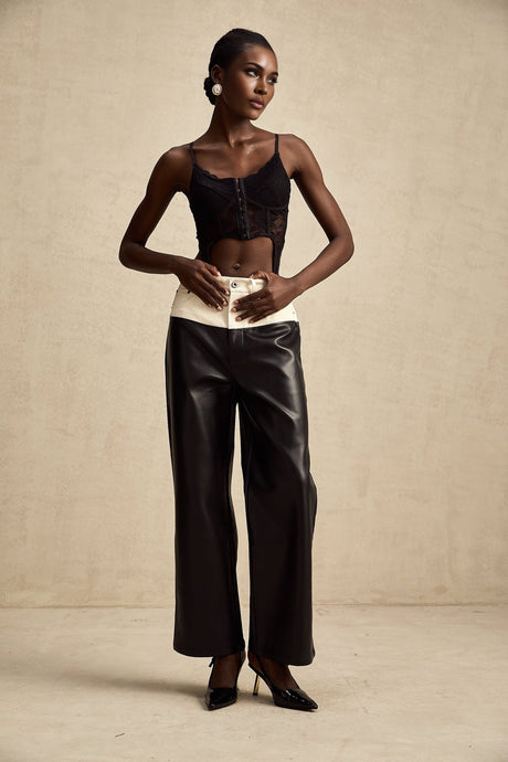 Woman wearing black leather trousers with white side stripes standing in casual pose