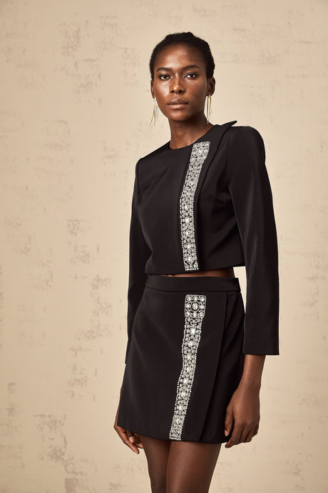 Woman wearing black matching set consisting of crystalembellished top and skirt named Nadia