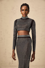 Woman wearing black matching set consisting of rhinestone mesh top and skirt with sparkly details