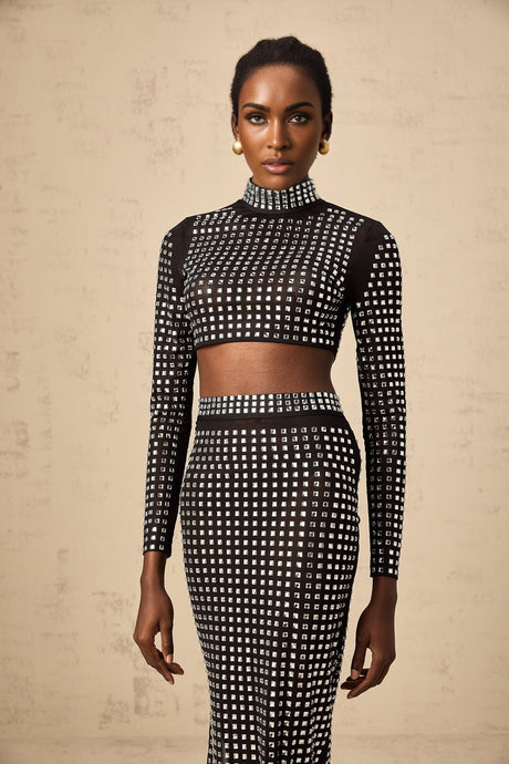 Woman wearing black matching set consisting of rhinestone mesh top and skirt with sparkly details