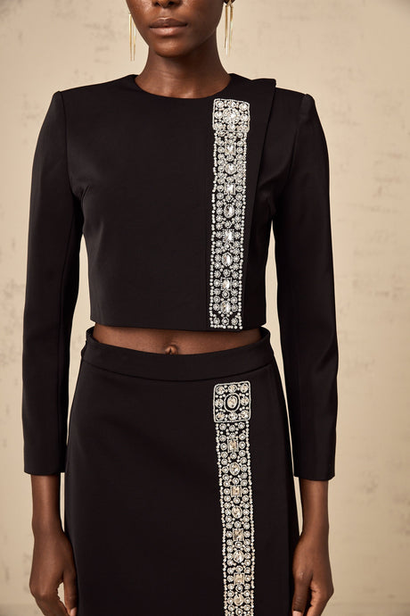 Woman wearing black matching set with crystal embellished sleeveless top and skirt