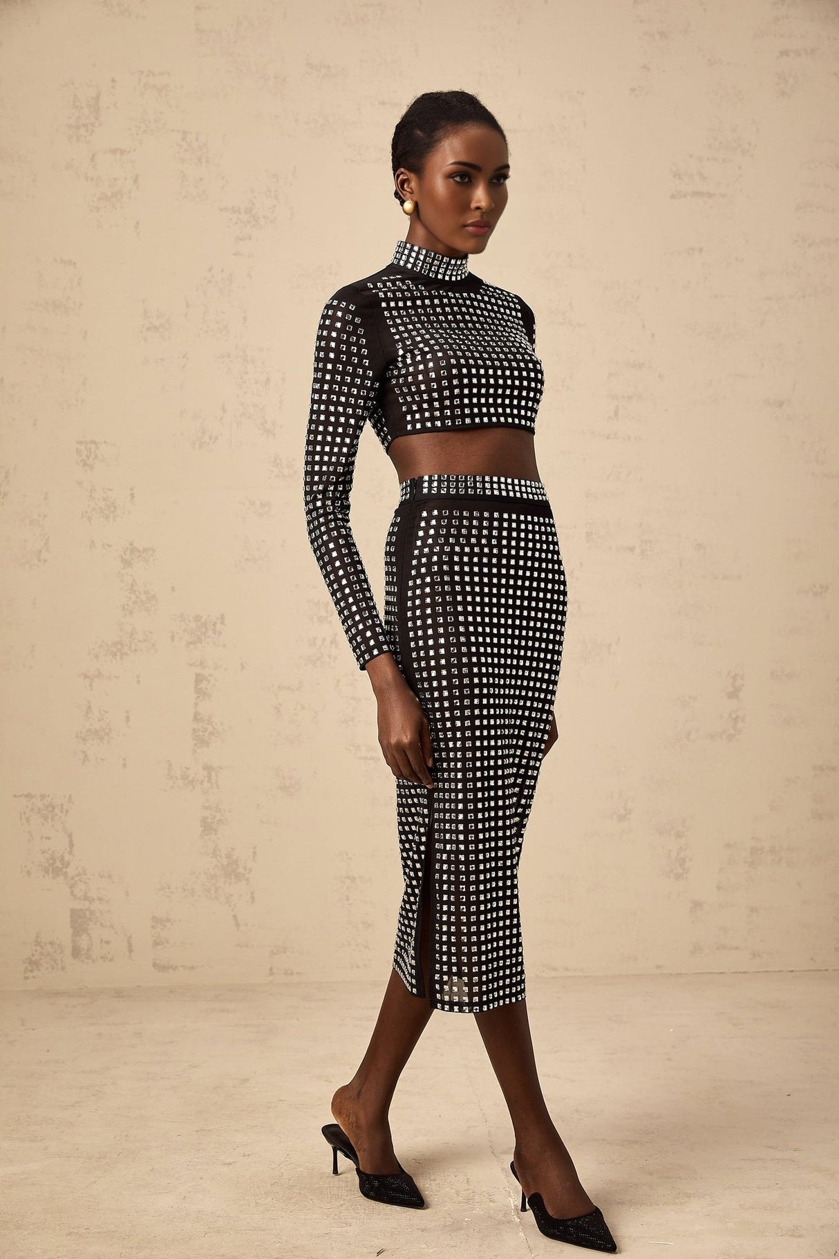 Woman wearing black mesh top and skirt set with rhinestone embellishments elegant sleeveless bodycon design