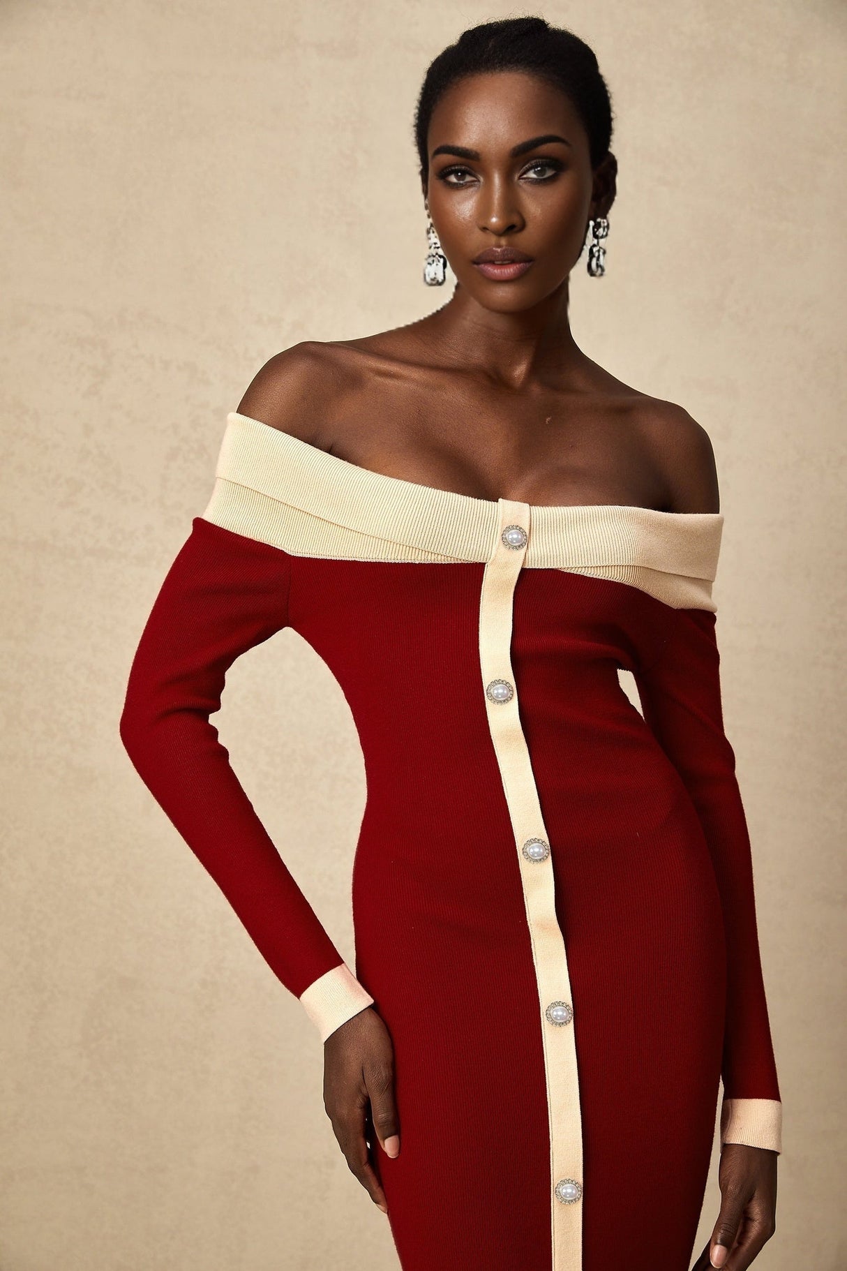 Woman wearing black offshoulder knit midi dress with long sleeves standing against white background