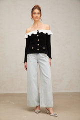 Woman wearing black offshoulder top with ruffled neckline