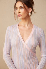 Woman wearing black pleated knit midi dress with V neckline and long sleeves standing in neutral background