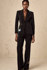 Woman wearing black sequined blazer and matching trousers standing in elegant pose