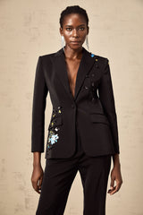 Woman wearing black sequined blazer and matching trousers standing in stylish pose