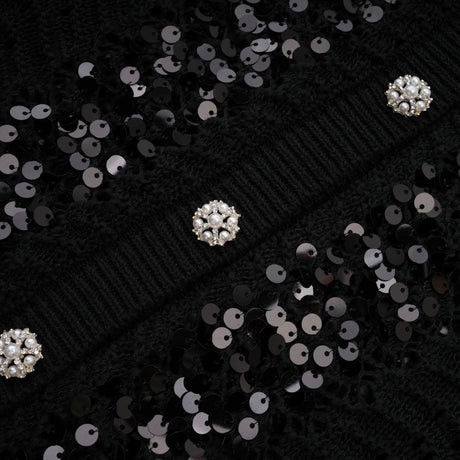 Woman wearing black sequined cardigan and matching skirt set with crochet knit texture