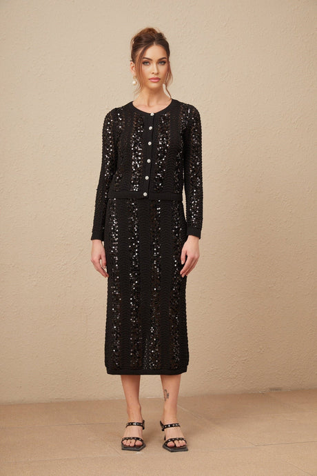 Woman wearing black sequined crochet cardigan and matching skirt set Ophelie design shimmering texture form fitting silhouette