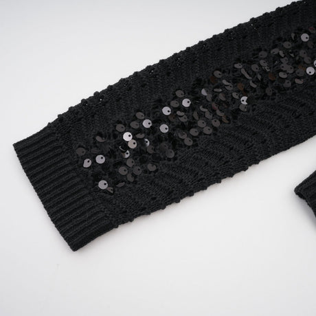 Woman wearing black sequined crochet cardigan and matching skirt set with sparkly texture