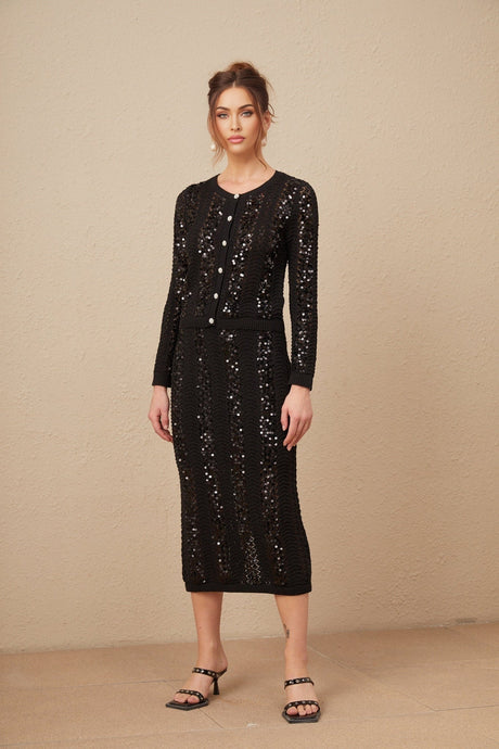 Woman wearing black sequined crochet knit cardigan and matching skirt set Ophelie style