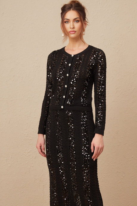 Woman wearing black sequined crochet knit cardigan and matching skirt set