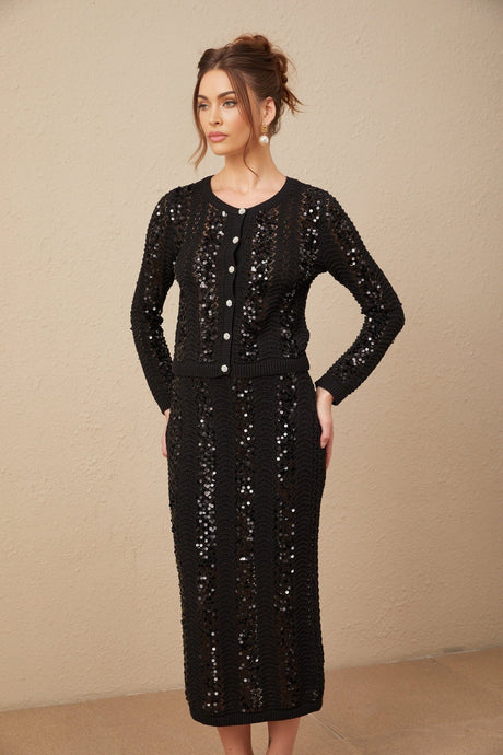 Woman wearing black sequined crochet knit cardigan and matching skirt set