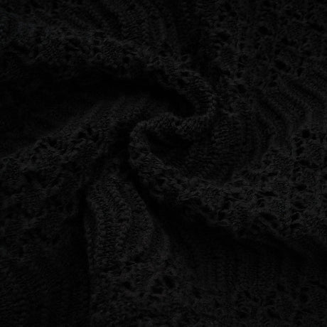 Woman wearing black sequined crochet knit cardigan and matching skirt set