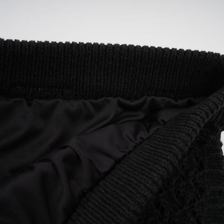 Woman wearing black sequined crochet knit cardigan and matching skirt set
