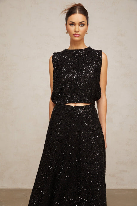 Woman wearing black sequined knit vest and matching skirt set shimmering outfit for evening wear