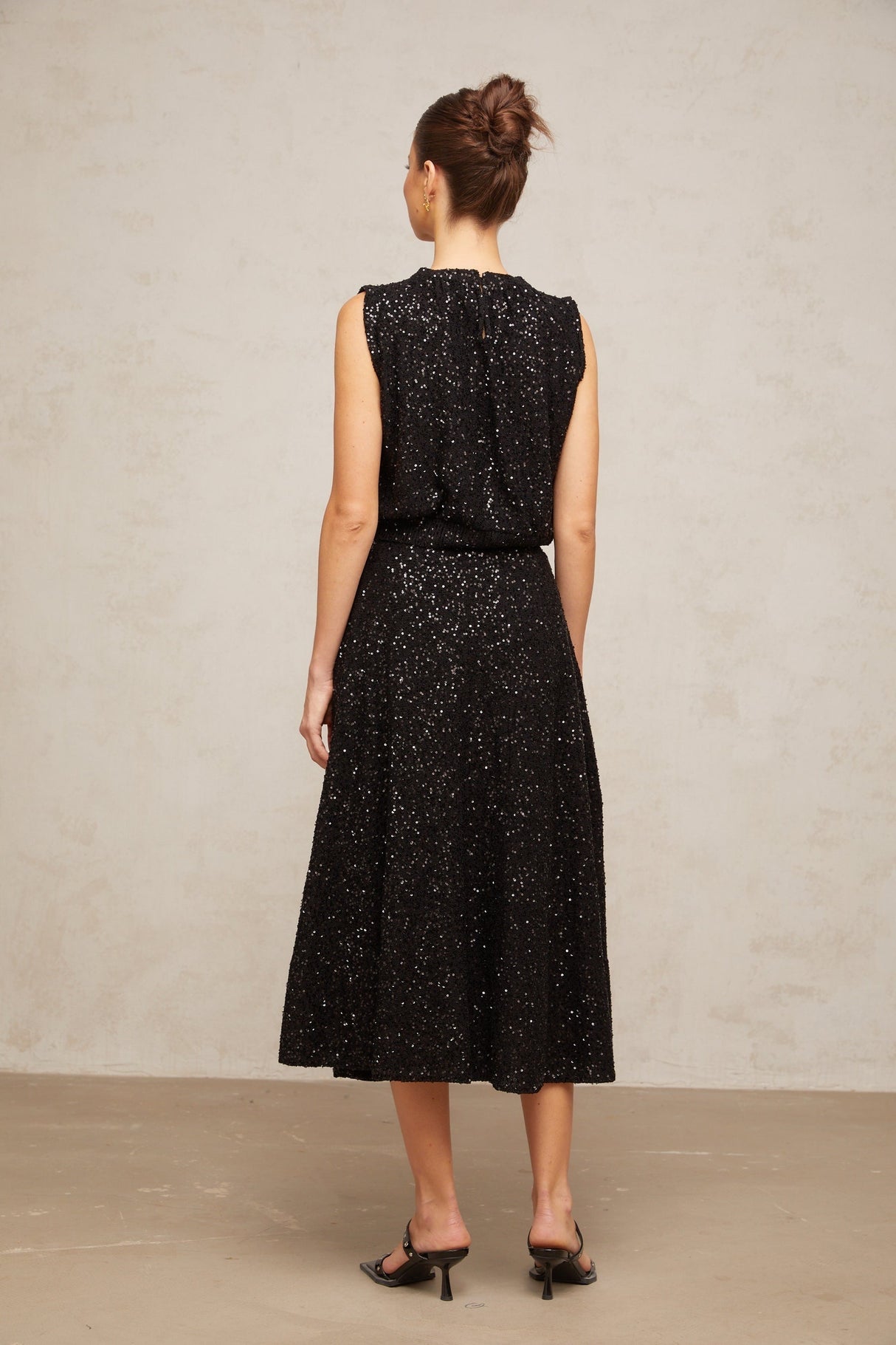 Woman wearing black sequined knit vest and matching skirt set Ulrique outfit shimmering sleeveless top with coordinating bottom
