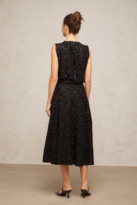 Woman wearing black sequined knit vest and matching skirt set Ulrique outfit shimmering sleeveless top with coordinating bottom