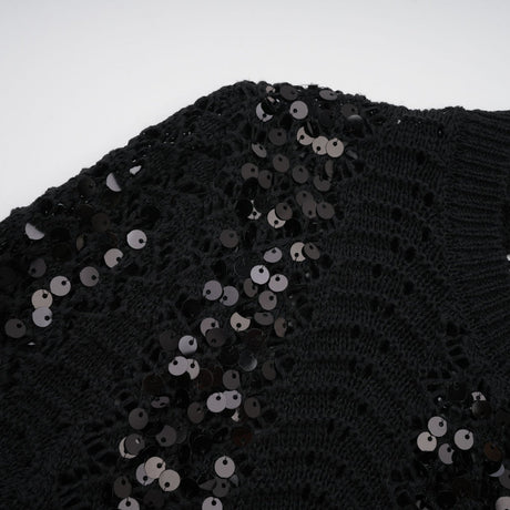 Woman wearing black sequined matching set with crochet knit cardigan and skirt