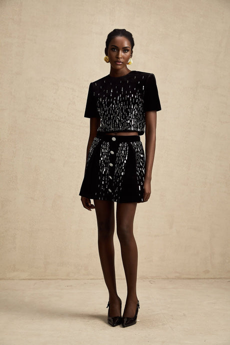 Woman wearing black velvet matching set consisting of embellished top and skirt called Isabeau