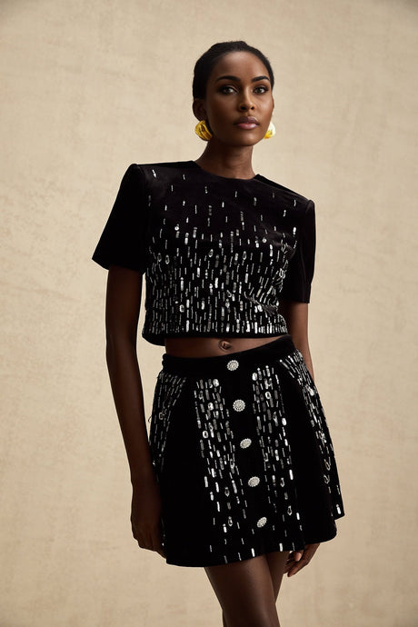 Woman wearing black velvet matching set with embellished top and skirt named Isabeau