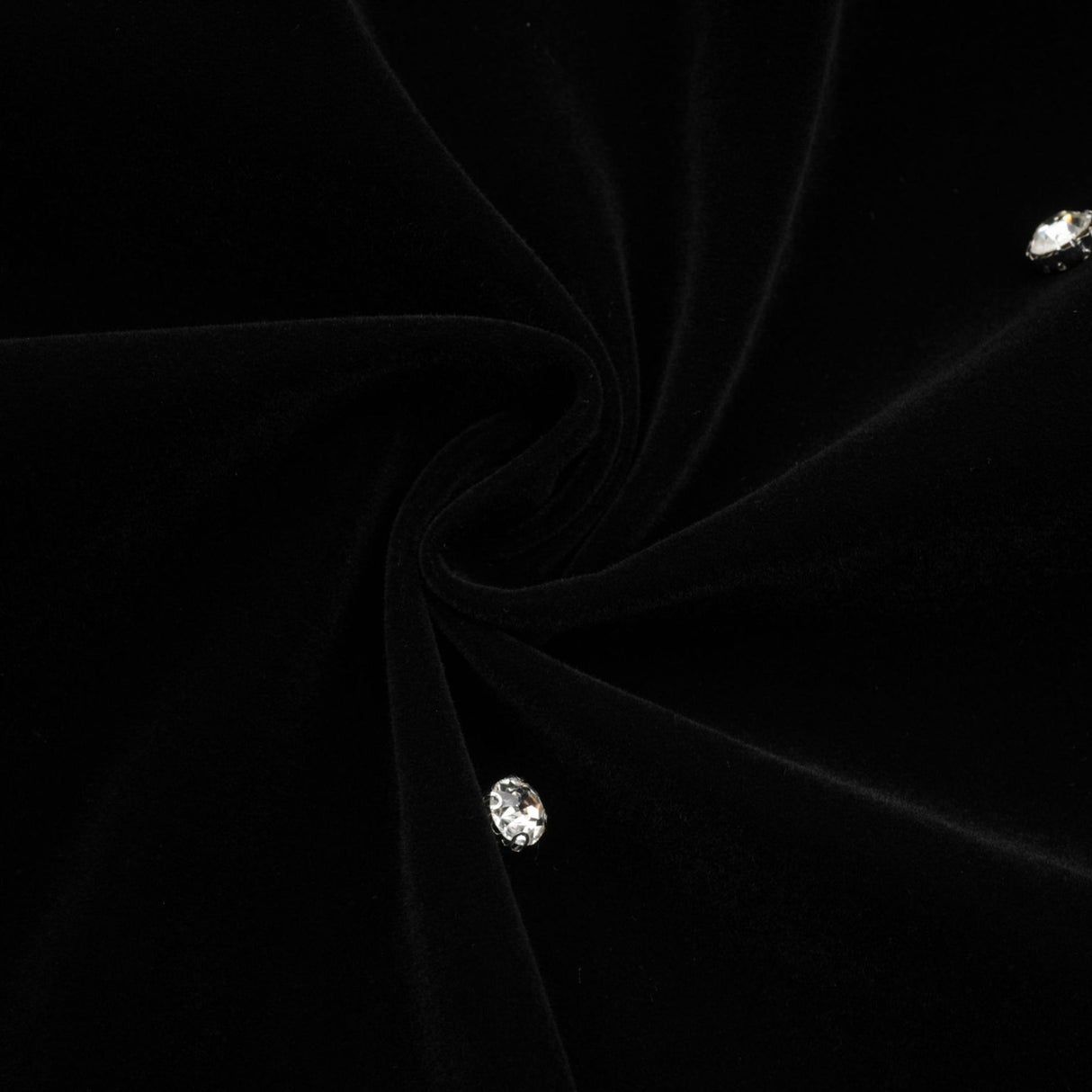 Woman wearing black velvet midi dress with embellishments form fitting silhouette sleeveless design