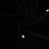 Woman wearing black velvet midi dress with embellishments form fitting silhouette sleeveless design
