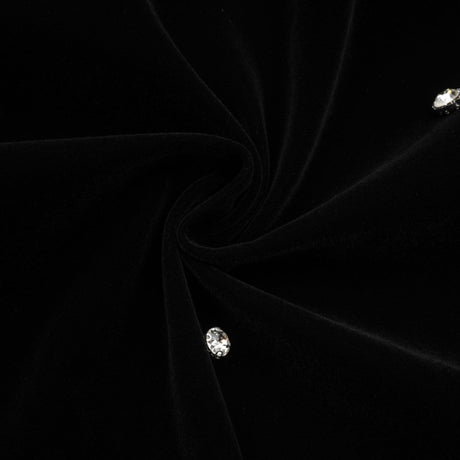Woman wearing black velvet midi dress with embellishments form fitting silhouette sleeveless design