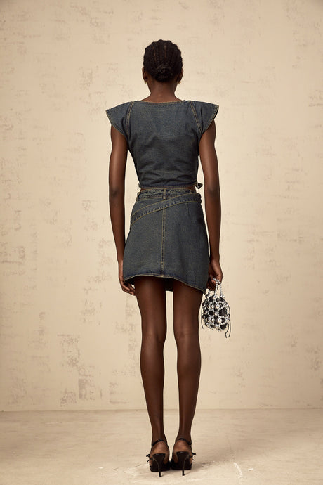Woman wearing blue denim crop top with crossover front and matching high waisted skirt set
