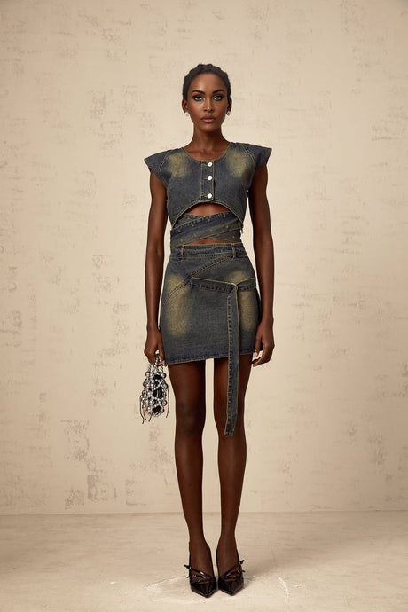 Woman wearing blue denim matching set consisting of a crossover top and skirt with fanny pack style details