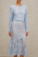 Woman wearing blue floral lace crop top and matching skirt set against plain background